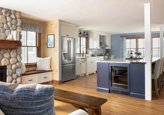 This first-floor renovation features a custom fireplace, remodeled kitchen with custom cabinetry, large kitchen island, and new windows.